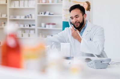 A male pharmacist on the phone helping a patient