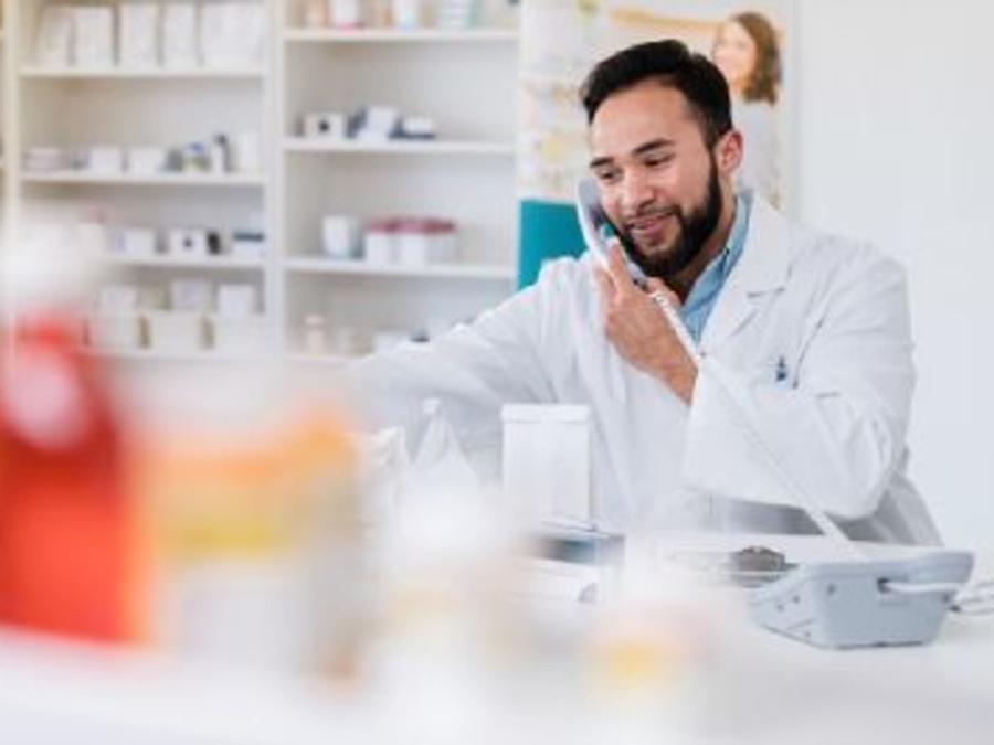 A smiling male pharmacist on the phone helping a patient