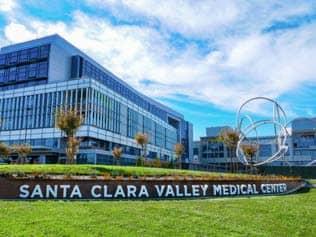 The front of the Santa Clara County Medical Center Building with a silver art sculpture next to the building.